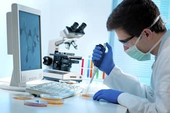Medical laboratory scientist working with a microscope, samples and diagnostic equipment in a modern laboratory